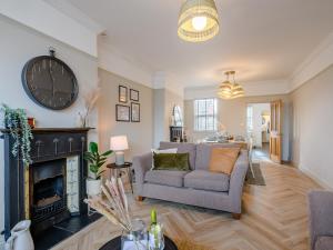 a living room with a couch and a clock on the wall at Wisteria Cottage in Heacham