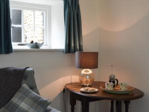 une table avec une lampe placée à côté d'une chaise dans l'établissement Sunny Cottage, à Bulmer