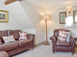 ein Wohnzimmer mit zwei Ledersesseln und einer Lampe in der Unterkunft Blackcurrant Cottage At Stanton Ford Farm in Baslow