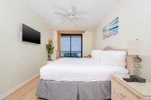 a bedroom with a bed with a ceiling fan and a television at Phoenix X 212 condo in Orange Beach