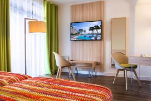 sypialnia z łóżkiem, biurkiem i telewizorem w obiekcie Hôtel Vacances Bleues Delcloy w mieście Saint-Jean-Cap-Ferrat