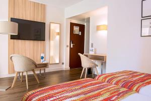 a bedroom with a bed and a desk and a television at Hôtel Vacances Bleues Delcloy in Saint-Jean-Cap-Ferrat