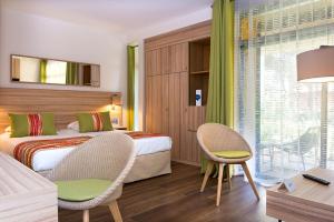 a hotel room with two beds and a table and chairs at Hôtel Vacances Bleues Delcloy in Saint-Jean-Cap-Ferrat