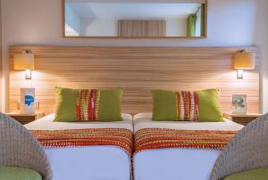 a bedroom with two beds with two chairs and a mirror at Hôtel Vacances Bleues Delcloy in Saint-Jean-Cap-Ferrat
