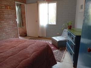 une chambre avec un lit, une chaise et une fenêtre dans l'établissement Casa Boreal dptos estilo casa, à Puerto Madryn