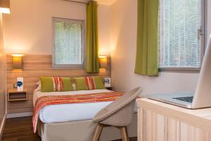 a bedroom with a bed and a laptop on a desk at Hôtel Vacances Bleues Delcloy in Saint-Jean-Cap-Ferrat