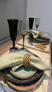 a table with two plates with napkins and wine glasses at Suite em Belo Horizonte com Vista e Piscina in Belo Horizonte