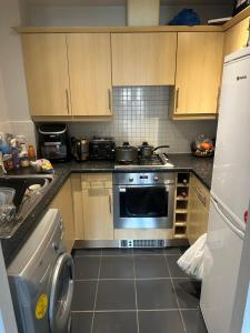 a kitchen with wooden cabinets and a stove and a washer at Little flat at the top in West Bromwich