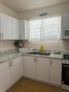 a kitchen with white cabinets and a sink and a window at Besos del Mar Ocean and Golf course view in Aguadilla