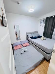 two beds in a small room with a mirror at Davao 1BR Condo for 4 with Pool Near SM Lanang and Airport in Davao City
