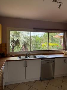 a kitchen with a sink and a large window at Maison bougainvilliers in Dumbéa +21 photos
