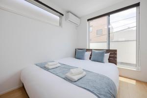 a bedroom with a white bed with a large window at First Choice Minami Kamata in Tokyo