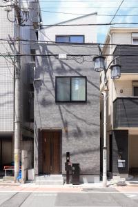 ein graues Gebäude mit einer braunen Tür an einer Straße in der Unterkunft First Choice Minami Kamata in Tokio