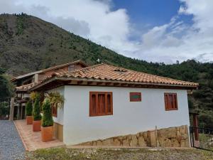 a white house with a mountain in the background at Casa Bahu Campestre in Villa de Leyva