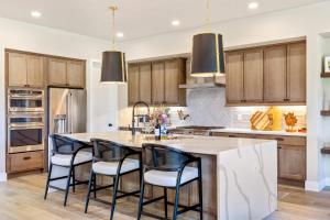 a kitchen with wooden cabinets and a large island with bar chairs at Pagoda Peaks - Modern Luxury Near Bozeman Beach in Bozeman