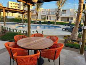 a wooden table and chairs with a table and a pool at Casa Las Palmas in Mazatlán