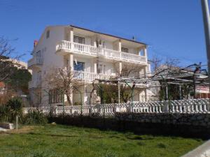 a large white house with a fence in front of it at Guest House Silvia in Rab