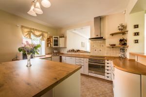 a kitchen with white cabinets and a wooden counter top at Karklės Villa - Prie Jūros in Karklė