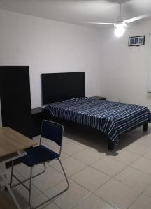 a bed in a room with a chair and a table at Depas Anahuac in Monterrey