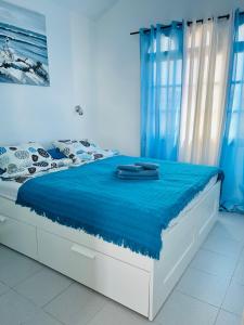 a bed with a blue blanket on top of it at Oasis del Sol in Costa Calma