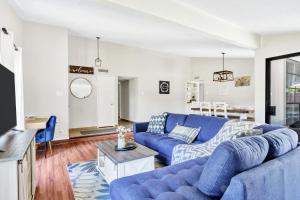 un salon avec un canapé bleu et une table dans l'établissement Jacuzzi & Pool House w/Game Room + Fire table, à The Colony
