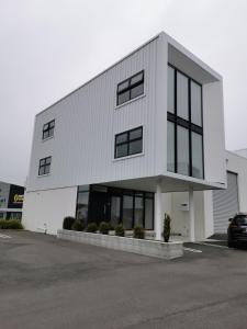 a white building with black windows in a parking lot at Mountain View Townhouse, New Plymouth in New Plymouth