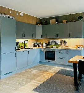eine große Küche mit blauen Schränken und einem Tisch in der Unterkunft Mountain Apartment With Views In Myrkdalen in Vossestrand