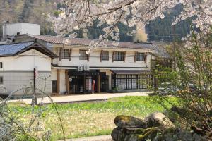 a building in the middle of a street withakura trees at Gokayama Onsen Akaokan in Nanto