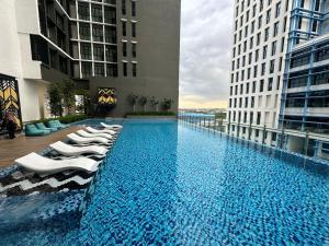 a large swimming pool with lounge chairs on a building at Alinea Suites by Adryan in Shah Alam