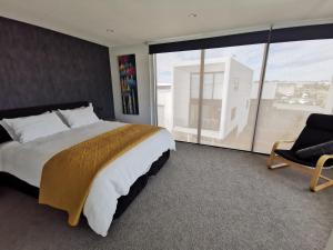 a bedroom with a bed and a chair and a large window at Mountain View Townhouse, New Plymouth in New Plymouth