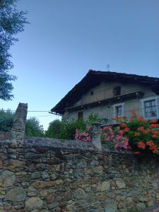 a stone wall with flowers in front of a house at La Casa Antica in Pont-Saint-Martin