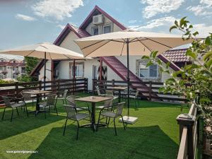 a group of tables and chairs with umbrellas in front of a house at Summer Vibe Costinesti in Costinesti