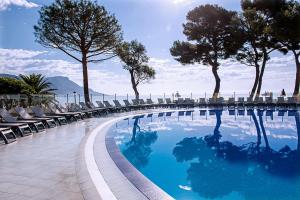 a swimming pool with chairs and trees on a building at Hôtel Vacances Bleues Delcloy in Saint-Jean-Cap-Ferrat