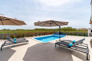 een zwembad met twee parasols en een zwembad bij Villa Anabel in Privlaka
