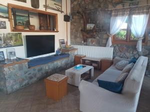 a living room with a tv and a couch and chairs at Agios Achillios in Agios Achillios