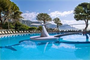 - une piscine avec une statue au milieu dans l'établissement Hôtel Vacances Bleues Delcloy, à Saint-Jean-Cap-Ferrat