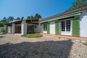 a house with green shutters and a yard at Villa Hokiss Piscine privée dans parc 1 hectare in Le Muy