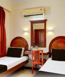 a room with two beds and a table and a mirror at Hotel comfort stay in Bengaluru