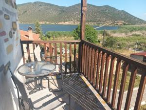 a table and chairs on a balcony with a view of a lake at Agios Achillios in Agios Achillios