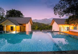 a swimming pool in front of a house at Munnar Majestic Resort with Pool in Munnar