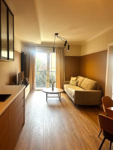 a living room with a couch and a table at Downtown Apartments Podpromie Monica with UNDERGROUND PARKING in Rzeszów +6 photos