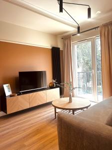 a living room with a tv and a couch and a table at Downtown Apartments Podpromie Monica with UNDERGROUND PARKING in Rzeszów