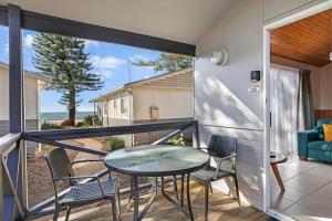 a balcony with a glass table and chairs at Kendalls Beach Holiday Park in Kiama