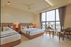 a hotel room with two beds and a table and chairs at Hotel Sunshine Inn, Somnath in Somnath