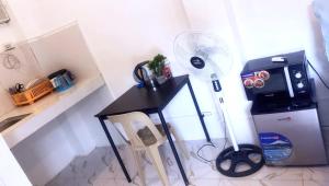 a room with a desk with a fan and a refrigerator at Centrally located studio 1 with AC and kitchenette in Coron
