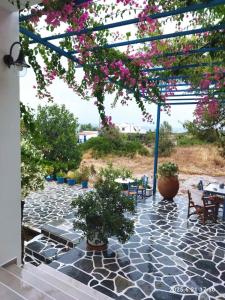 un patio con tavoli, sedie e fiori rosa di Hotel Flisvos a Megalochori (Isola di Agistri)