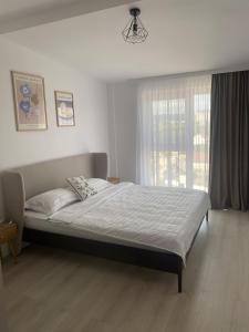 a bed in a bedroom with a large window at Home Away Bistrița in Bistriţa