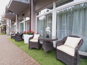 a patio with wicker chairs and a table and windows at Pensjonat Plażowy Boss z Restauracją 50 metrów od Morza in Dziwnów