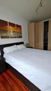 a bedroom with a white bed with three paintings on the wall at Apartamento Amura cerca de Costa Quebrada in Sancibrián