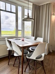 a dining room with a wooden table and white chairs at Ferienwohnung De Krabb in Dorum